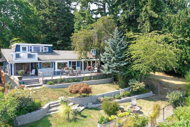 rear view of house with a tile roof, a fenced backyard, a yard, a balcony, and a patio area