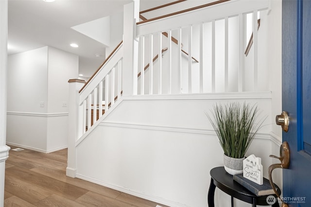 stairway featuring baseboards, wood finished floors, and recessed lighting