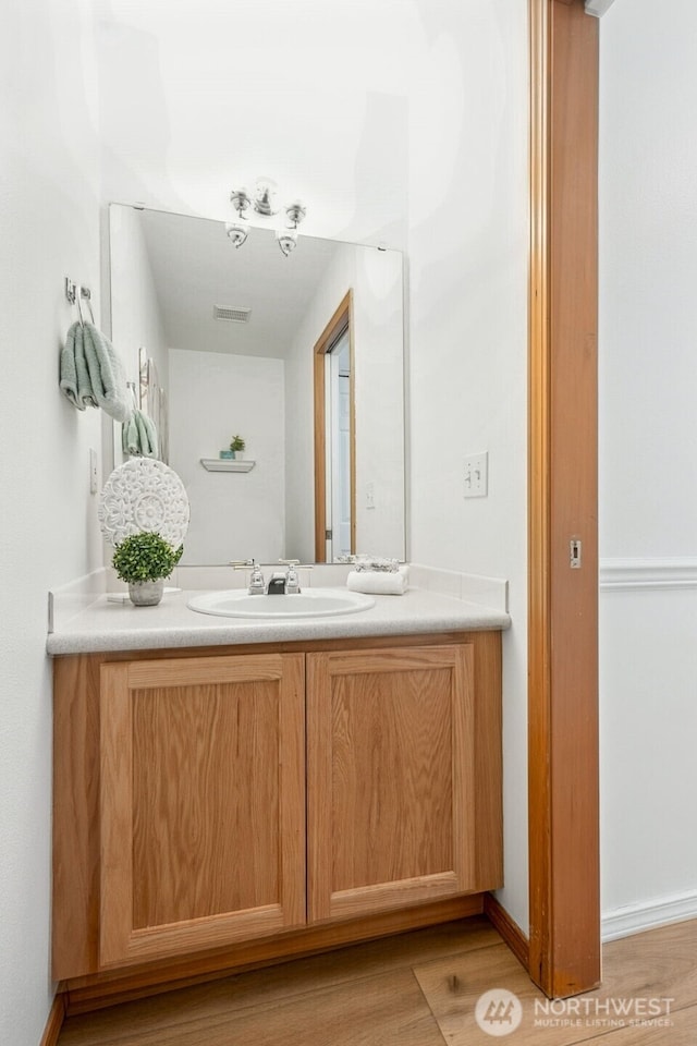 bathroom with baseboards, visible vents, wood finished floors, and vanity