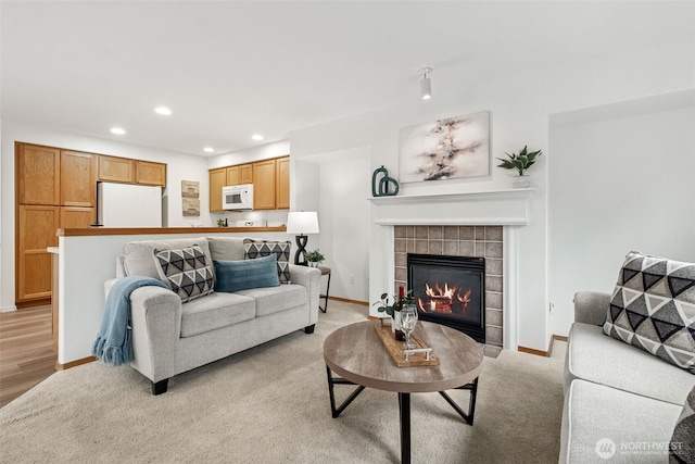 living room featuring recessed lighting, light carpet, a fireplace, and baseboards