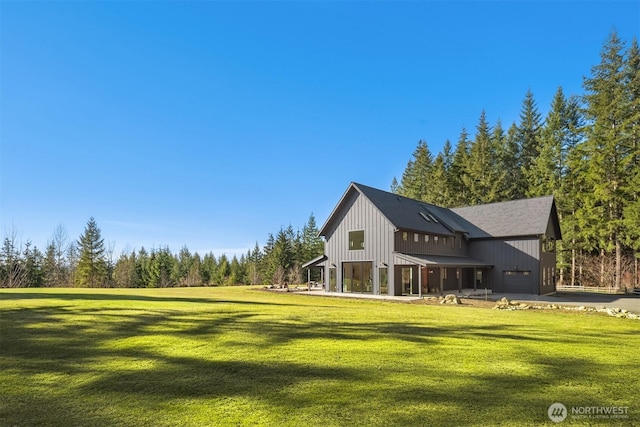 back of property with a yard, an attached garage, and driveway