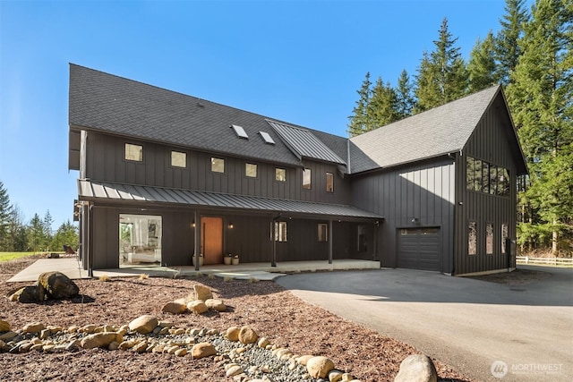 modern inspired farmhouse with a porch, board and batten siding, a standing seam roof, metal roof, and driveway