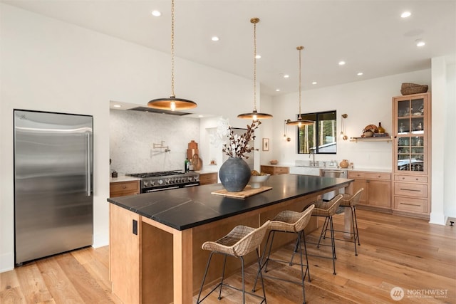 kitchen featuring tasteful backsplash, high quality appliances, a kitchen island, a kitchen breakfast bar, and light wood-type flooring