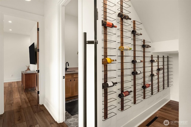 wine cellar with lofted ceiling, dark wood-type flooring, a sink, and baseboards