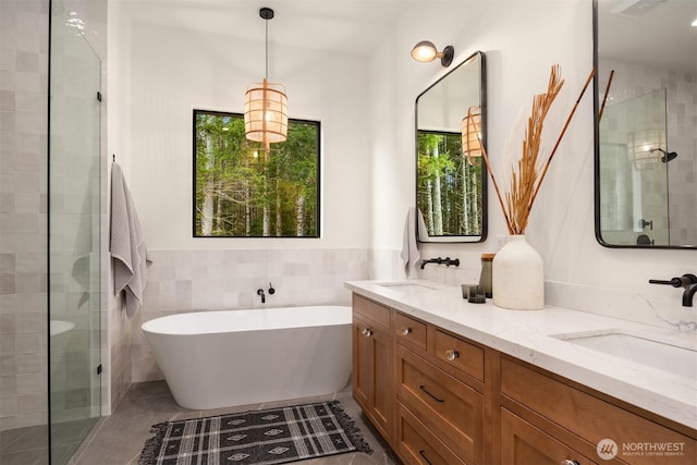 bathroom featuring a tile shower, double vanity, and a sink