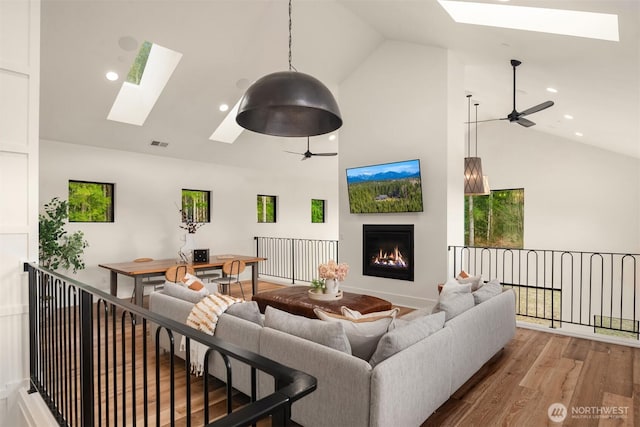 living room featuring a skylight, visible vents, wood finished floors, a lit fireplace, and recessed lighting