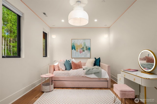 bedroom with multiple windows, crown molding, baseboards, and wood finished floors