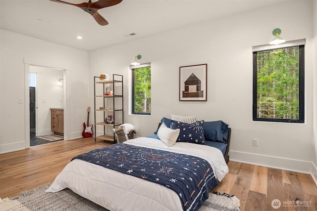 bedroom with ensuite bathroom, recessed lighting, wood finished floors, visible vents, and baseboards