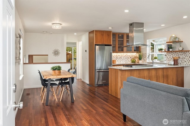 kitchen with a healthy amount of sunlight, brown cabinetry, island range hood, and stainless steel appliances