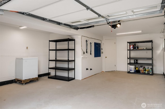 garage featuring fridge, electric panel, and a garage door opener