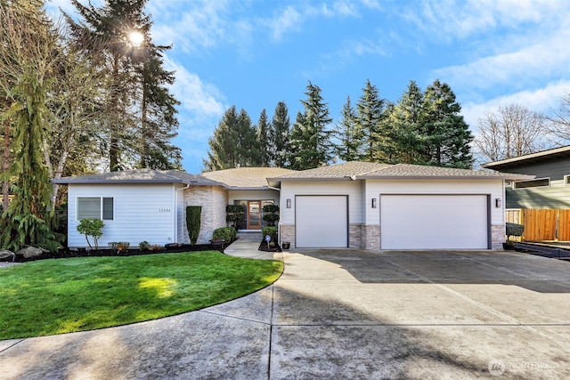 view of front of home with concrete driveway, an attached garage, a front yard, fence, and stone siding