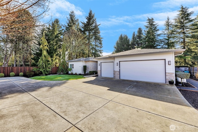 ranch-style house with a front yard, fence, stone siding, an outdoor structure, and driveway