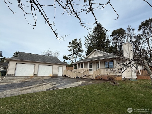 view of front of house featuring a detached garage, a chimney, covered porch, a front yard, and an outdoor structure