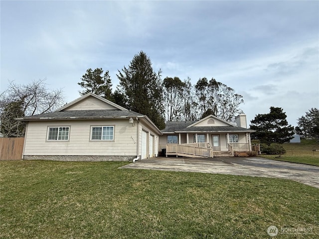 view of front facade with a porch, an attached garage, a front yard, fence, and driveway