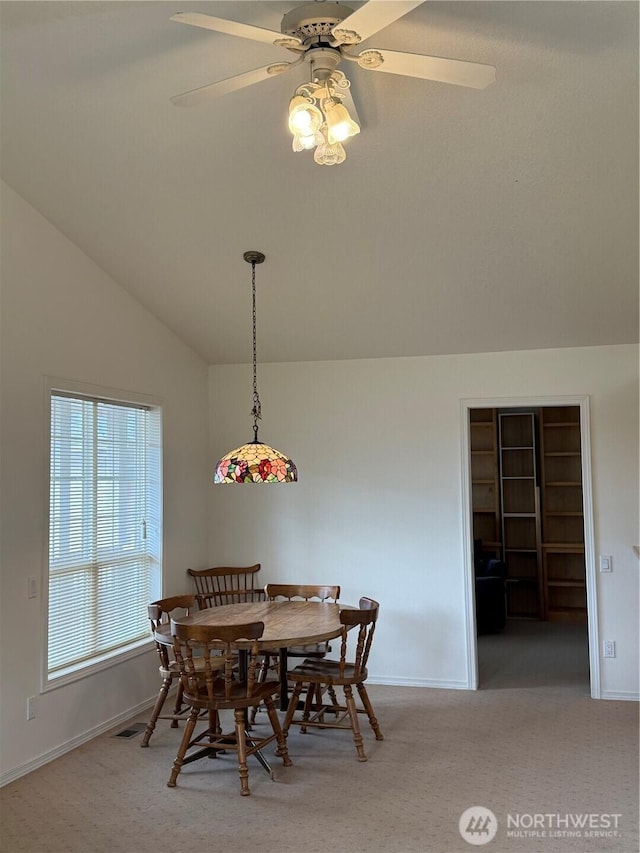 carpeted dining area with baseboards, vaulted ceiling, and a ceiling fan