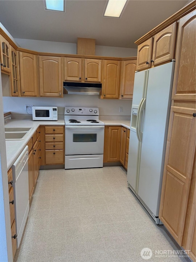 kitchen with under cabinet range hood, white appliances, a sink, light floors, and glass insert cabinets