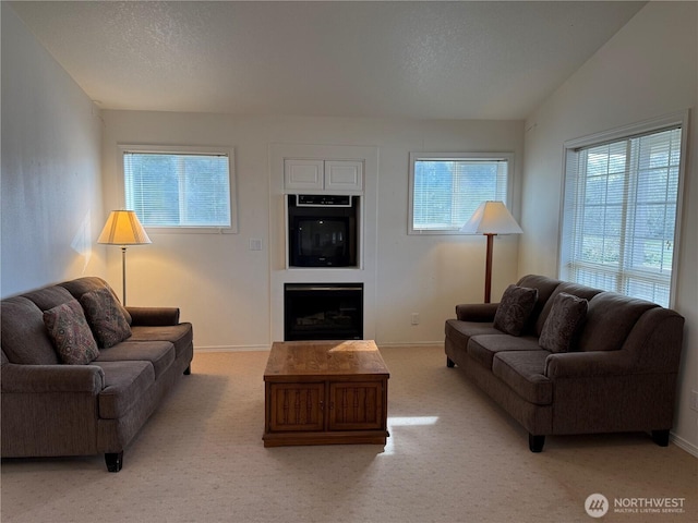 living room featuring light carpet, a textured ceiling, plenty of natural light, and a fireplace