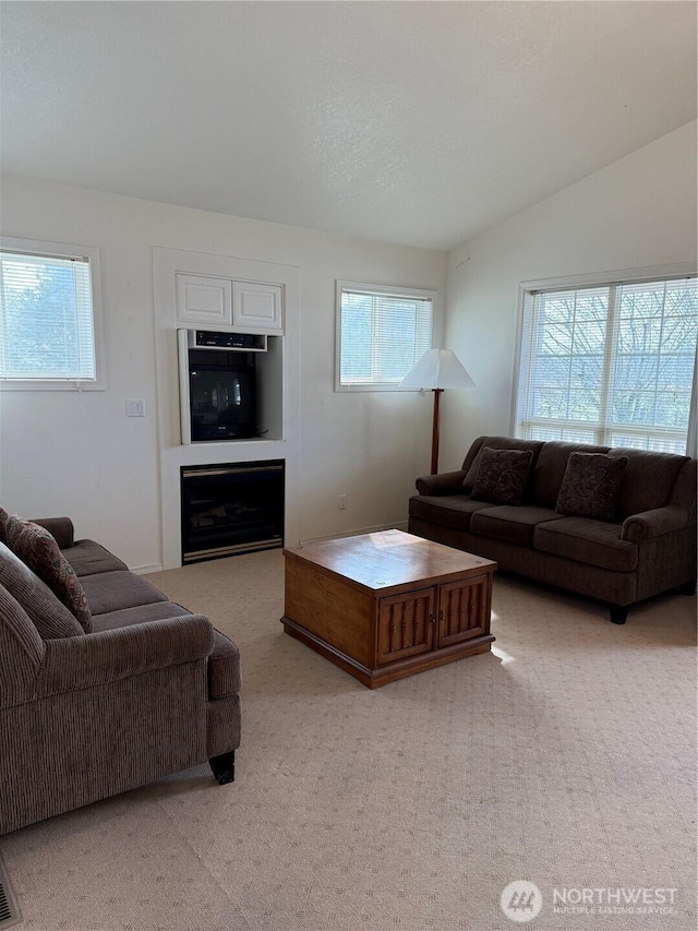 living room featuring light carpet, vaulted ceiling, and a fireplace