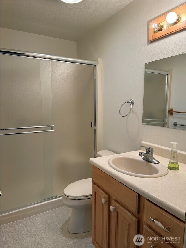 bathroom featuring toilet, a stall shower, tile patterned flooring, and vanity