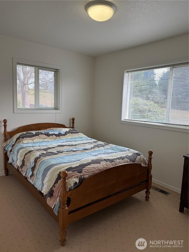 bedroom featuring baseboards, visible vents, a textured ceiling, and light colored carpet