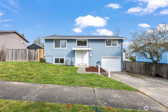 bi-level home featuring a front yard, an attached garage, driveway, and fence