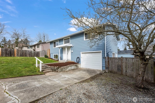 split foyer home featuring a garage, driveway, a front lawn, and fence