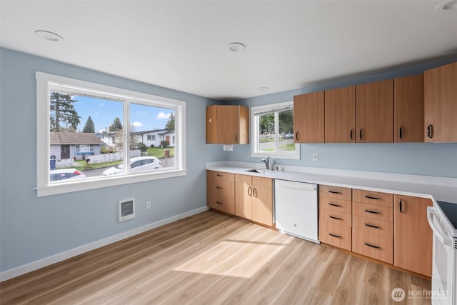 kitchen with visible vents, light wood-type flooring, a sink, white appliances, and baseboards