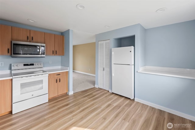 kitchen featuring light wood finished floors, white appliances, light countertops, and baseboards