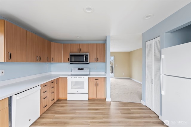 kitchen with light wood finished floors, baseboards, light brown cabinetry, light countertops, and white appliances