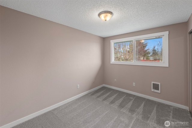 spare room featuring carpet flooring, a textured ceiling, and baseboards