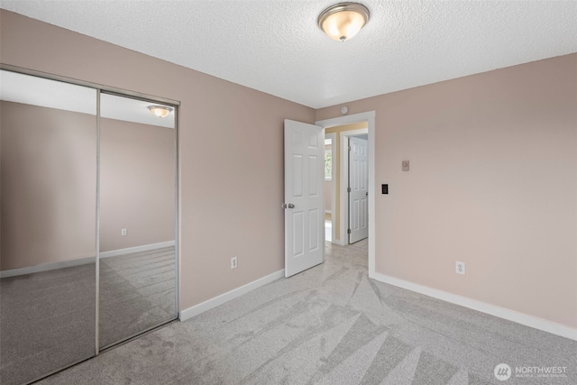 unfurnished bedroom featuring carpet flooring, baseboards, a closet, and a textured ceiling