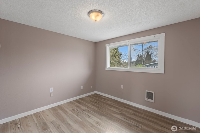 spare room with baseboards, a textured ceiling, and wood finished floors