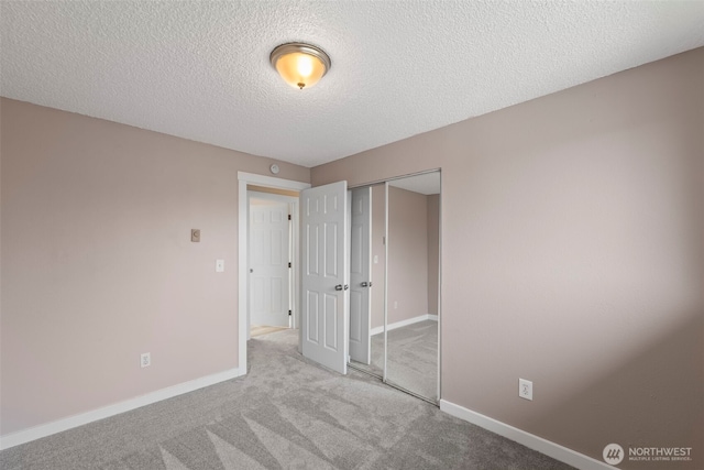 unfurnished bedroom with a closet, baseboards, a textured ceiling, and carpet flooring