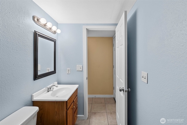 half bath featuring tile patterned floors, baseboards, toilet, and vanity