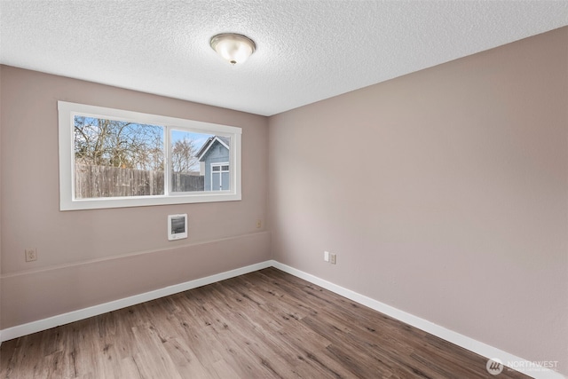 spare room with wood finished floors, baseboards, and a textured ceiling