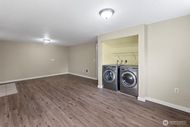 clothes washing area with laundry area, wood finished floors, baseboards, and washing machine and clothes dryer