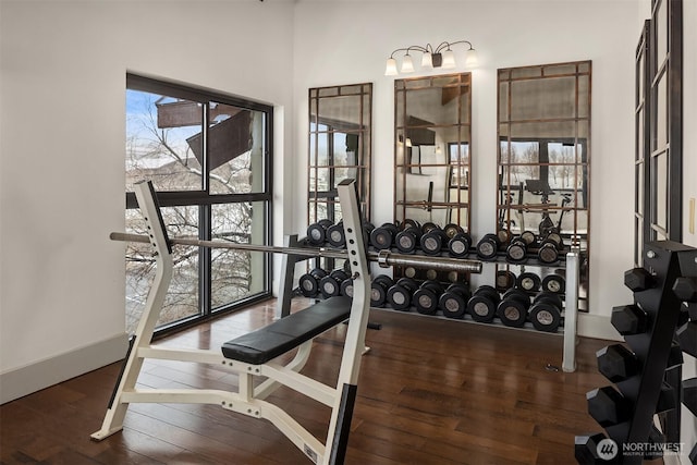 exercise room with baseboards and dark wood-type flooring