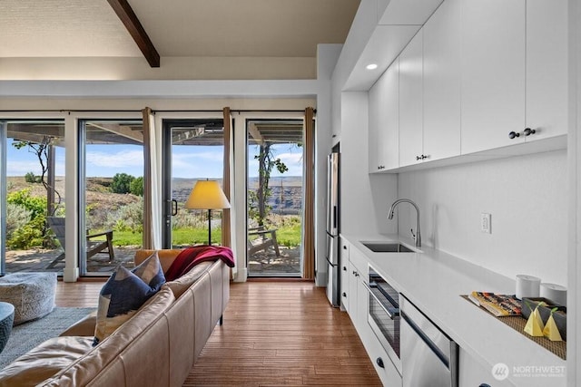344 Silica Rd NW Unit 8, Quincy, WA 98848 - kitchen featuring beamed ceiling, wood finished floors, light countertops, white cabinets, and freestanding refrigerator