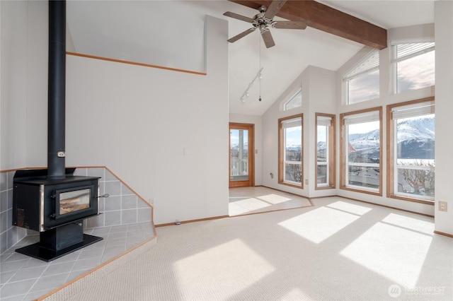 carpeted living room with high vaulted ceiling, a wood stove, a healthy amount of sunlight, and beamed ceiling