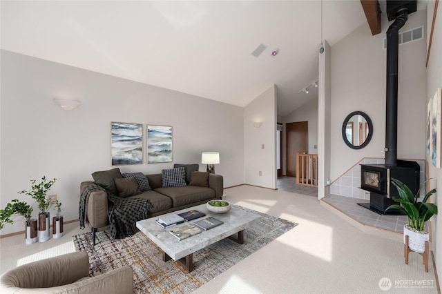 living room with high vaulted ceiling, carpet floors, visible vents, baseboards, and a wood stove