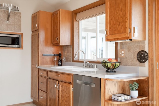 kitchen featuring stainless steel appliances, a sink, light countertops, and decorative backsplash