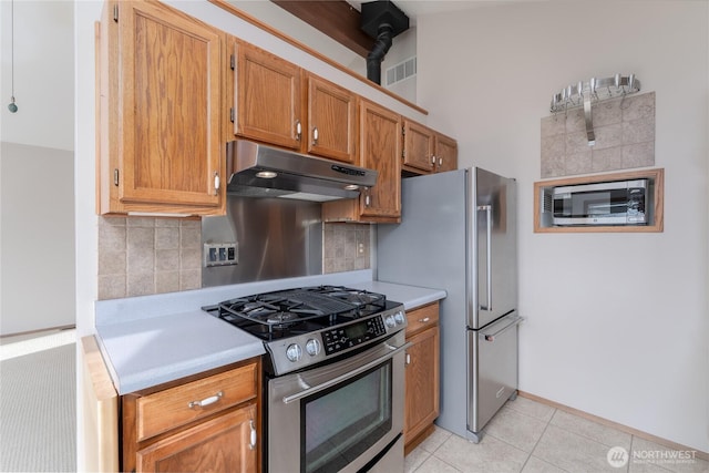 kitchen with stainless steel appliances, visible vents, light countertops, decorative backsplash, and under cabinet range hood