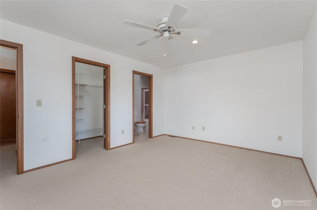 unfurnished bedroom with light carpet, baseboards, ensuite bath, a spacious closet, and a closet