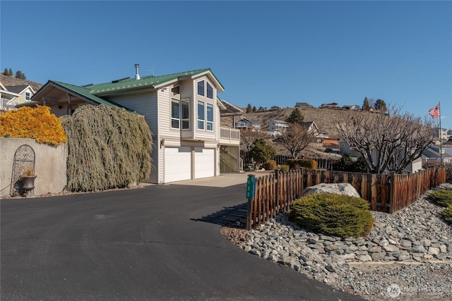 view of property exterior featuring metal roof, driveway, an attached garage, and fence