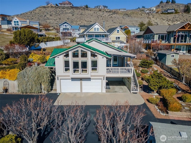 rear view of property with a garage, fence, driveway, stairway, and a residential view