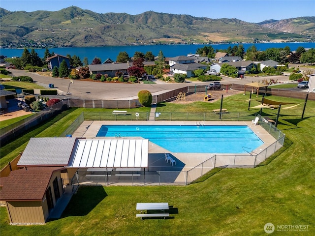 pool featuring a lawn, fence, and a water and mountain view