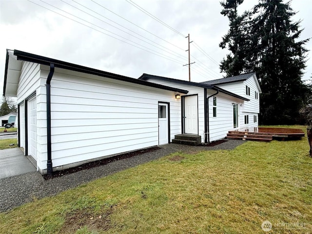 rear view of house featuring entry steps, a lawn, and a garage