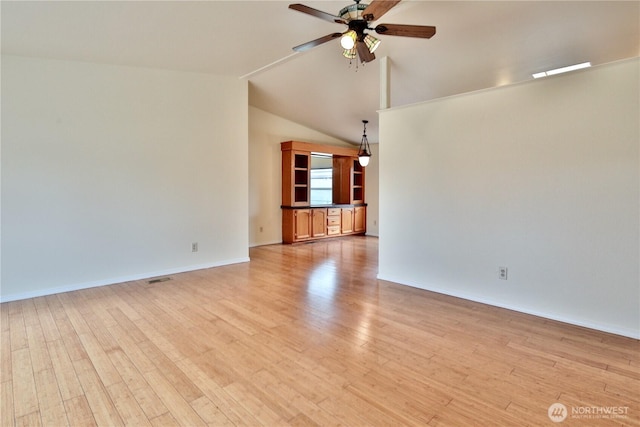 spare room featuring light wood-type flooring, visible vents, a ceiling fan, baseboards, and lofted ceiling