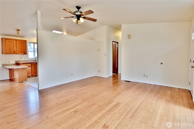 unfurnished living room with lofted ceiling, a ceiling fan, light wood finished floors, and a sink