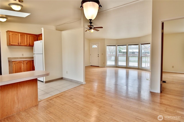 kitchen featuring a skylight, freestanding refrigerator, light countertops, light wood-style floors, and open floor plan